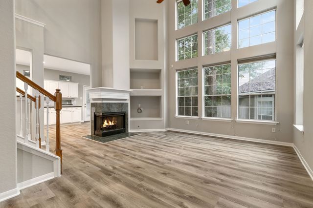 a view of an empty room with wooden floor fireplace and a window