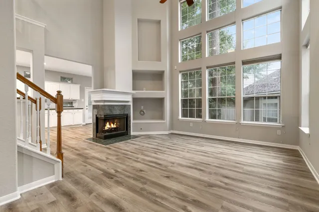 a view of an empty room with wooden floor fireplace and a window