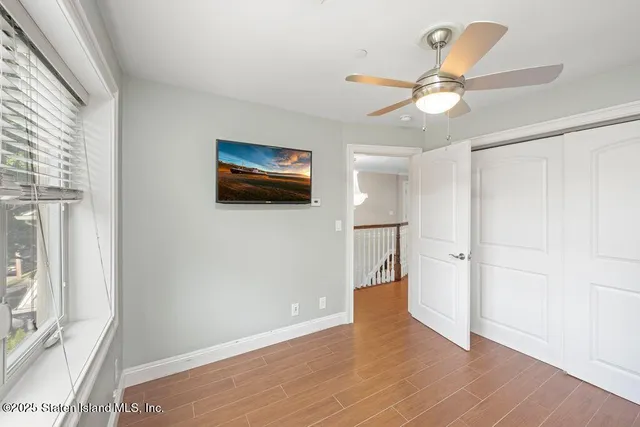 a view of empty room with wooden floor and fan