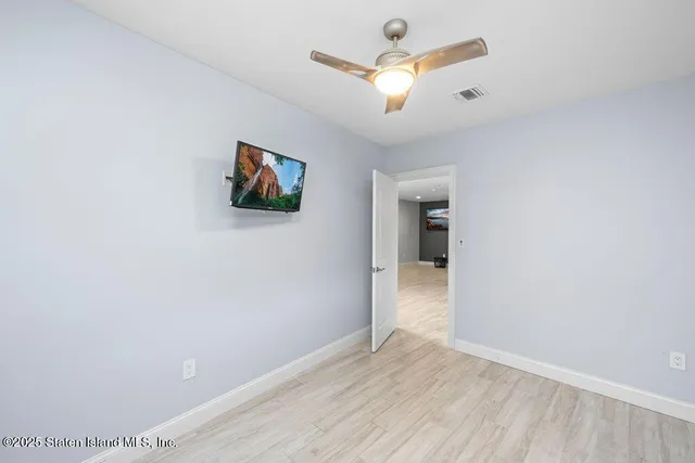 an empty room with wooden floor and ceiling fan