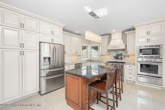 a kitchen with stainless steel appliances a refrigerator a stove a sink and white cabinets