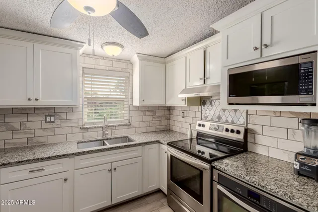 a kitchen with granite countertop a sink stainless steel appliances and cabinets