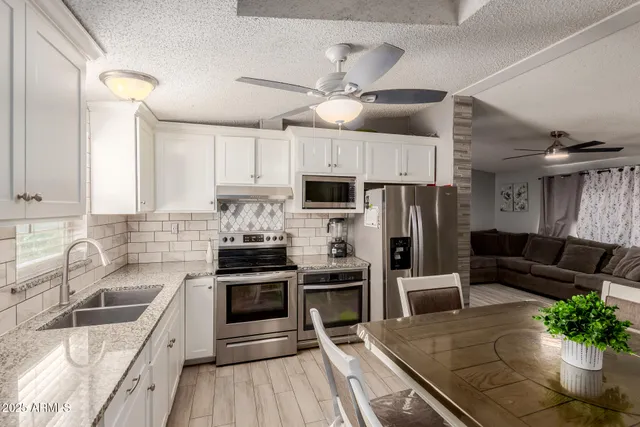 a kitchen with granite countertop a refrigerator a sink dishwasher stove and oven