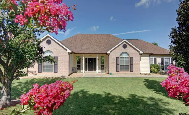 a front view of a house with a garden and trees