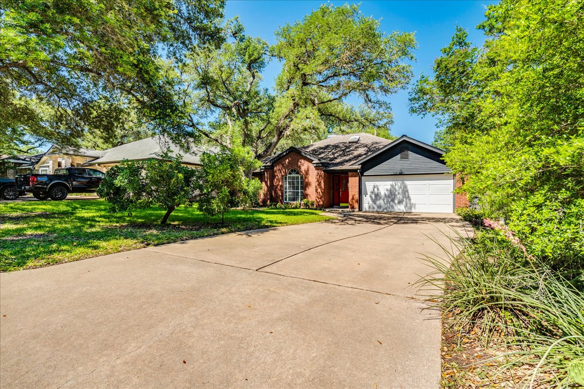 6530 Needham Lane Austin, TX 78739 - Photo 3 of 29 Generous driveway leads to a welcoming home framed by mature trees, enhancing its inviting facade.