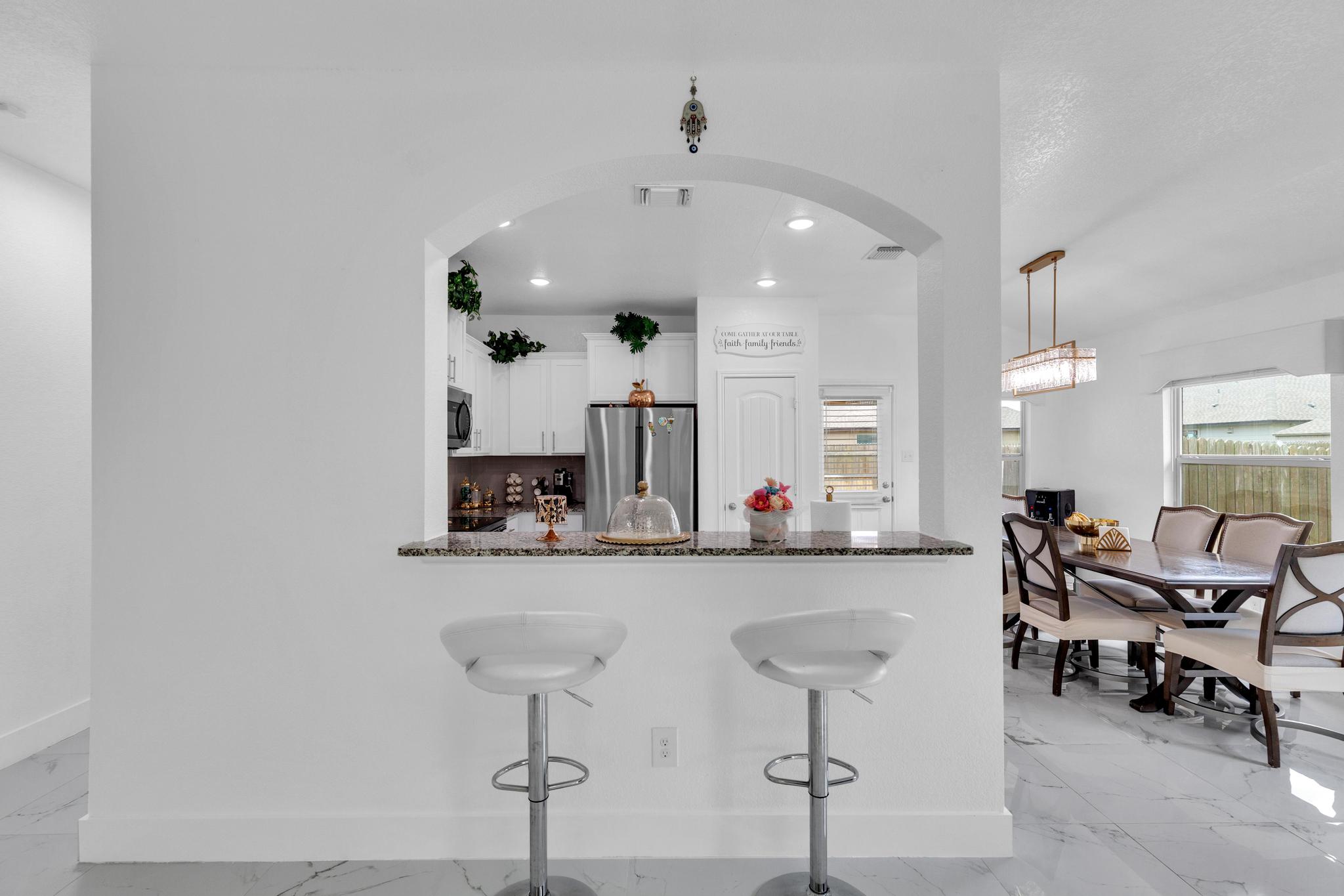 119 Beth Ann Loop Taylor, TX 76574 - Photo 10 of 31 An archway frames a stylish kitchen with bar seating, leading to a well-lit dining area.