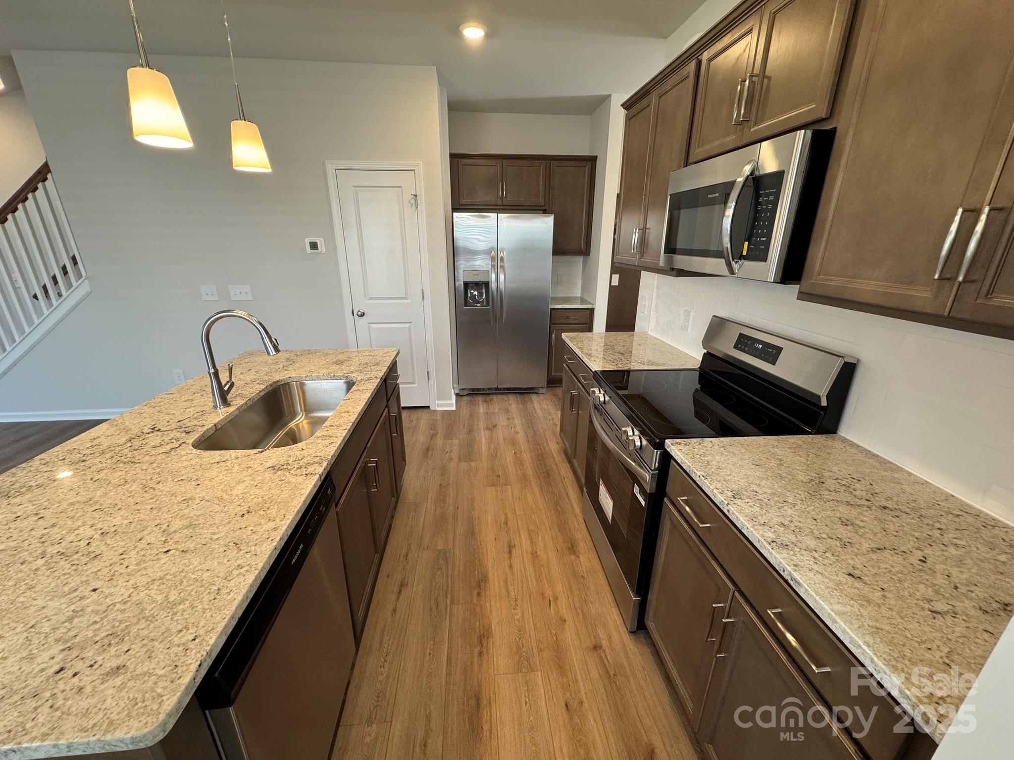 4720 Lakeview Road, Unit 12 Charlotte, NC 28216 - Photo 9 of 41 a kitchen with granite countertop a sink a stove top oven a refrigerator and wooden floor