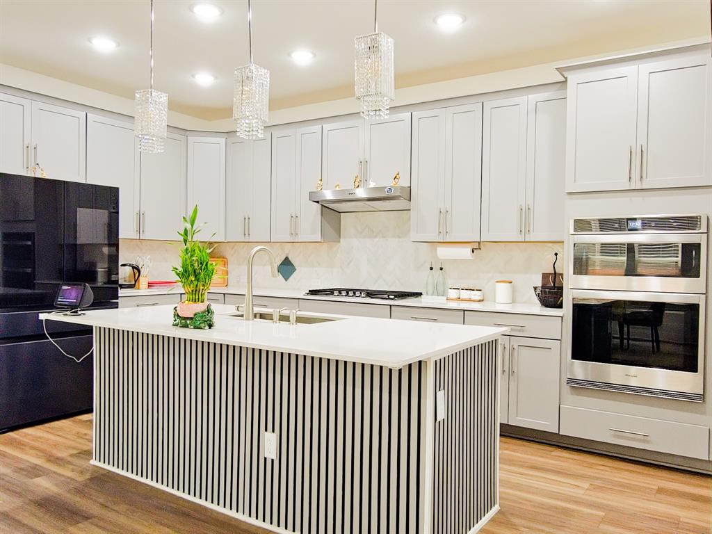 332 Turnbuckle Bend Leander, TX 78641 - Photo 13 of 34 Kitchen featuring a central island with slat paneling, white countertop, and a stainless steel sink with a gooseneck faucet