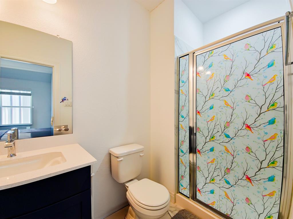 332 Turnbuckle Bend Leander, TX 78641 - Photo 23 of 34 Bathroom featuring a sliding glass shower enclosure with decorative film, a single vanity with a dark wood-finish cabinet, a white countertop, and a built-in sink with a chrome faucet