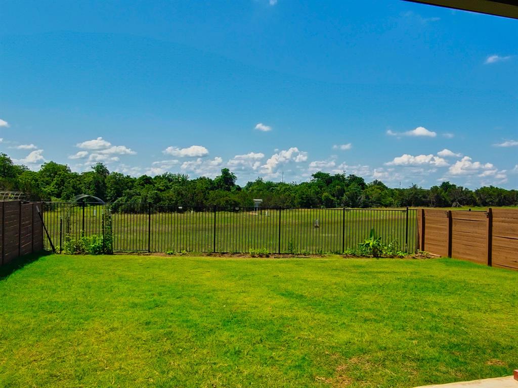 332 Turnbuckle Bend Leander, TX 78641 - Photo 33 of 34 Expansive grassy backyard featuring a wrought iron fence and wood privacy fencing