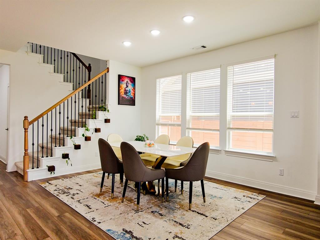 332 Turnbuckle Bend Leander, TX 78641 - Photo 7 of 34 Spacious dining area featuring wood-finish flooring, recessed lighting, and a prominent staircase with dark metal balusters and a wood handrail