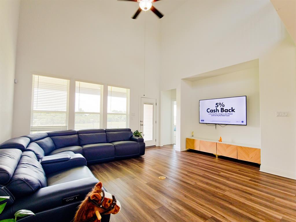 332 Turnbuckle Bend Leander, TX 78641 - Photo 8 of 34 Living room featuring soaring ceilings, wood-finish flooring, a ceiling fan, and multiple large windows with blinds