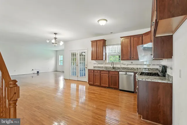a large kitchen with granite countertop a stove top oven a sink dishwasher and white cabinets with wooden floor