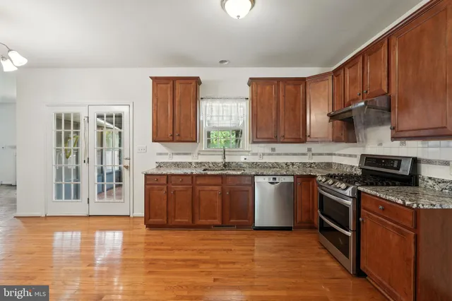 a kitchen with stainless steel appliances granite countertop wooden cabinets a stove top oven a sink and dishwasher
