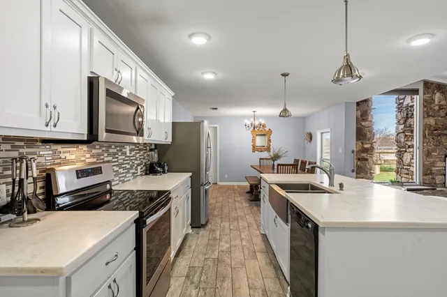 a kitchen with stainless steel appliances a sink stove refrigerator and cabinets