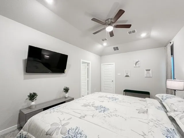 a bedroom with a bed a flat tv screen and a chandelier