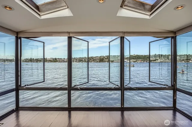 a view of an empty room with wooden floor and windows