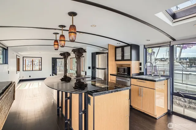 a view of a kitchen with stainless steel appliances granite countertop a stove a refrigerator and wooden floor