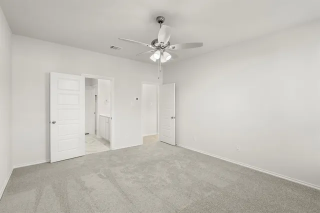 an empty room with a fan & a ceiling fan