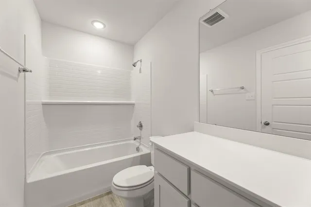 a bathroom with a granite countertop sink a toilet and shower