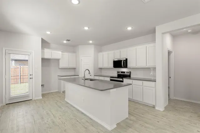 a large kitchen with stainless steel appliances granite countertop a stove a sink and a refrigerator