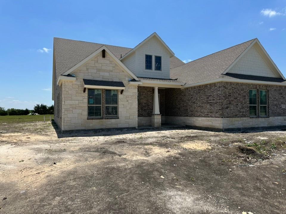 295 Brown Road Leonard, TX 75452 - Photo 4 of 26 Stone and brick exterior with a prominent front porch column, multi-pitched roofline, light siding accents on gables, and multiple windows