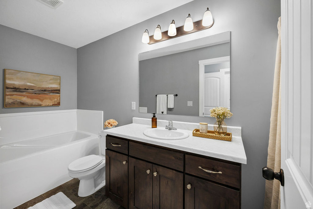 2483 South 1296th Street West Logan, UT 84321 - Photo 21 of 45 Bathroom featuring a white tub, toilet, and a dark wood-finish vanity with a white countertop and integrated sink