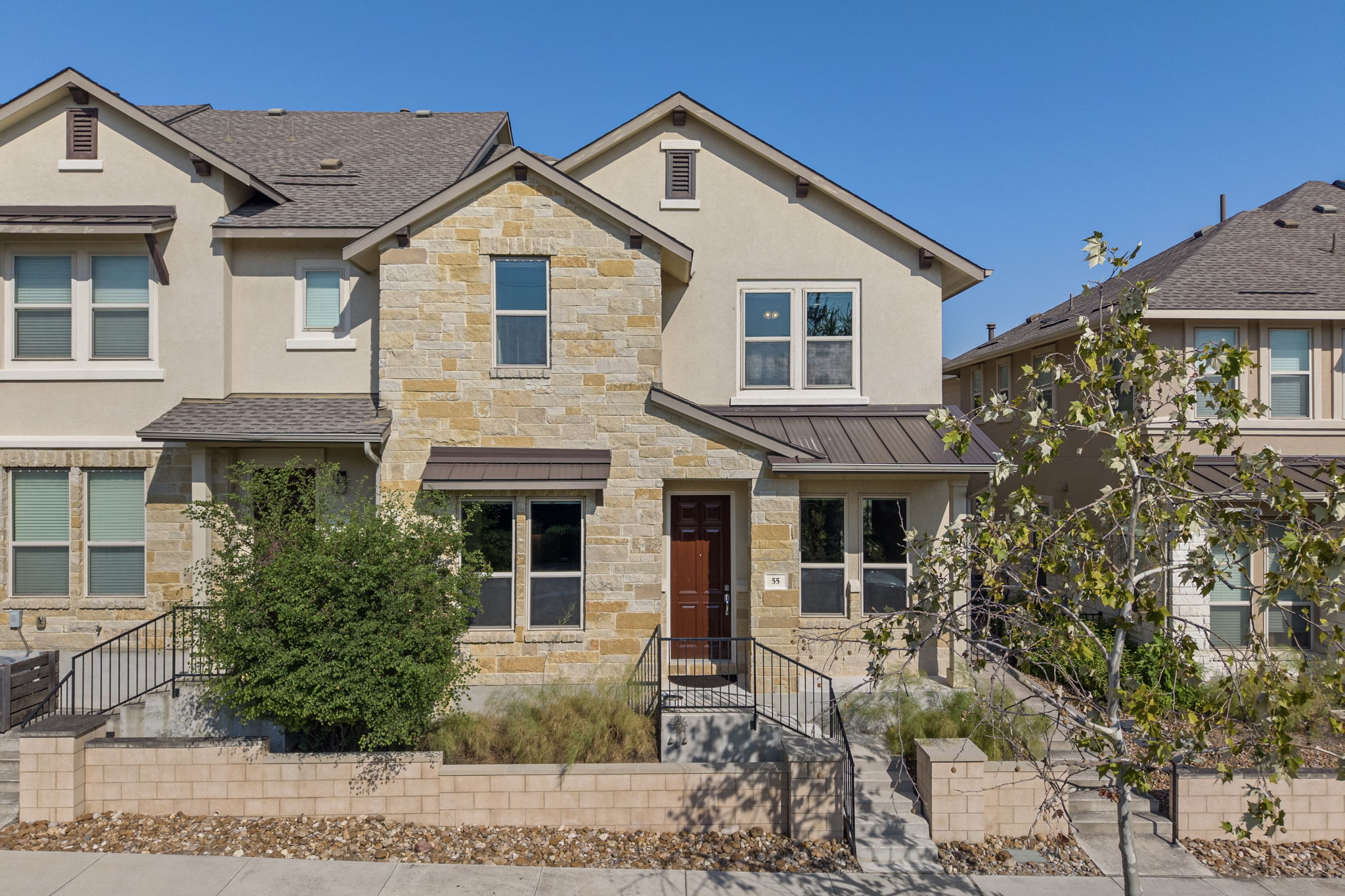 View of front of home with stone siding, stucco siding, and a metal roof