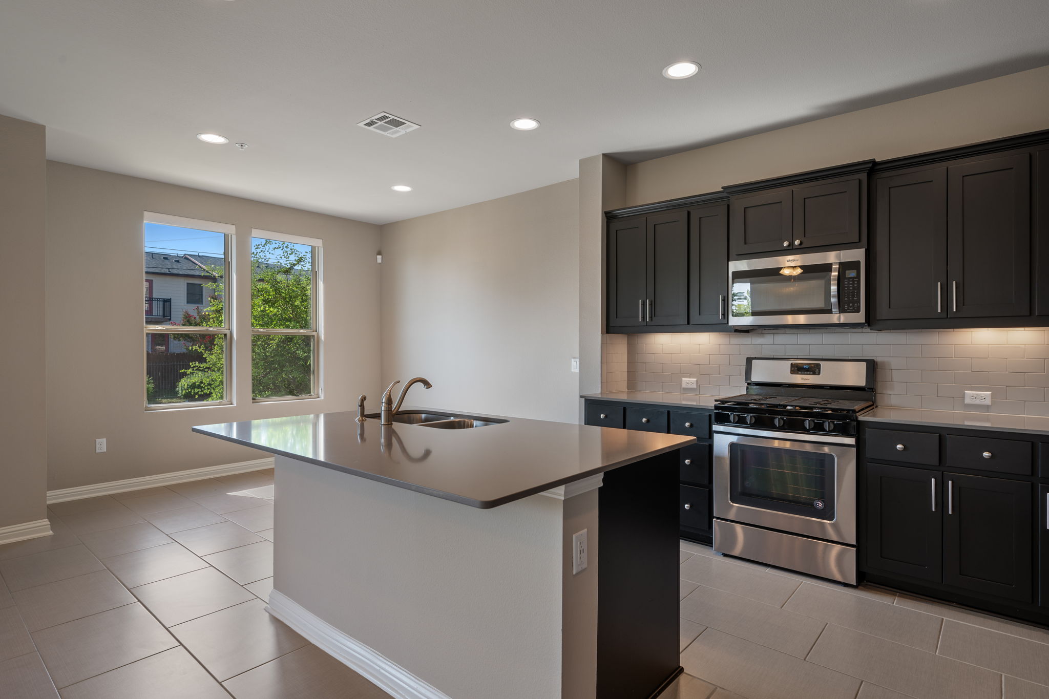 6814 East Riverside Drive, Unit 55 Austin, TX 78741 - Photo 10 of 31 Kitchen with stainless steel appliances, recessed lighting, light tile patterned floors, backsplash, and a kitchen island with sink