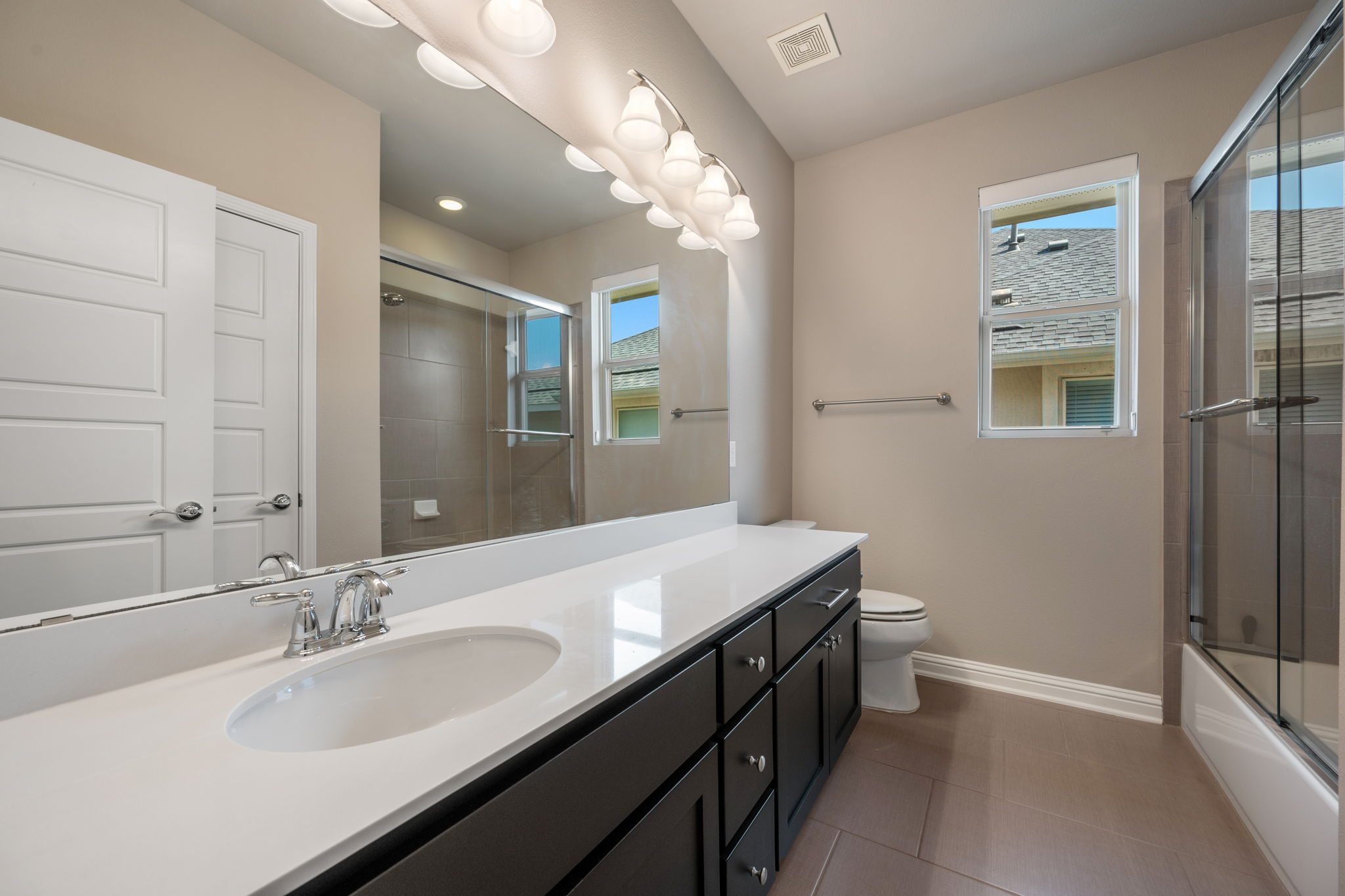 6814 East Riverside Drive, Unit 55 Austin, TX 78741 - Photo 25 of 31 Full bathroom with combined bath / shower with glass door, vanity, and dark tile patterned floors