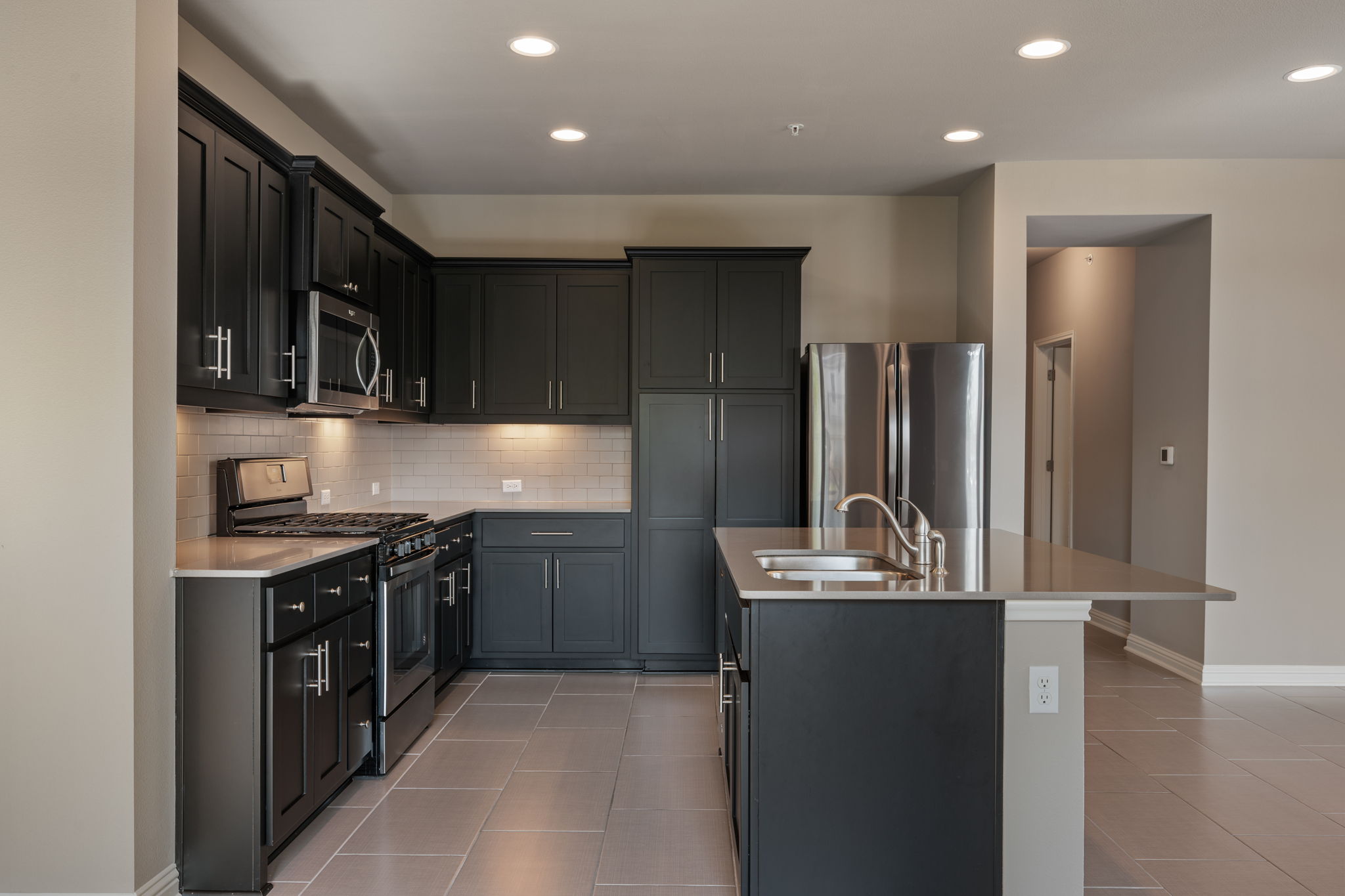 6814 East Riverside Drive, Unit 55 Austin, TX 78741 - Photo 9 of 31 Kitchen featuring stainless steel appliances, tasteful backsplash, recessed lighting, a center island with sink, and light stone countertops