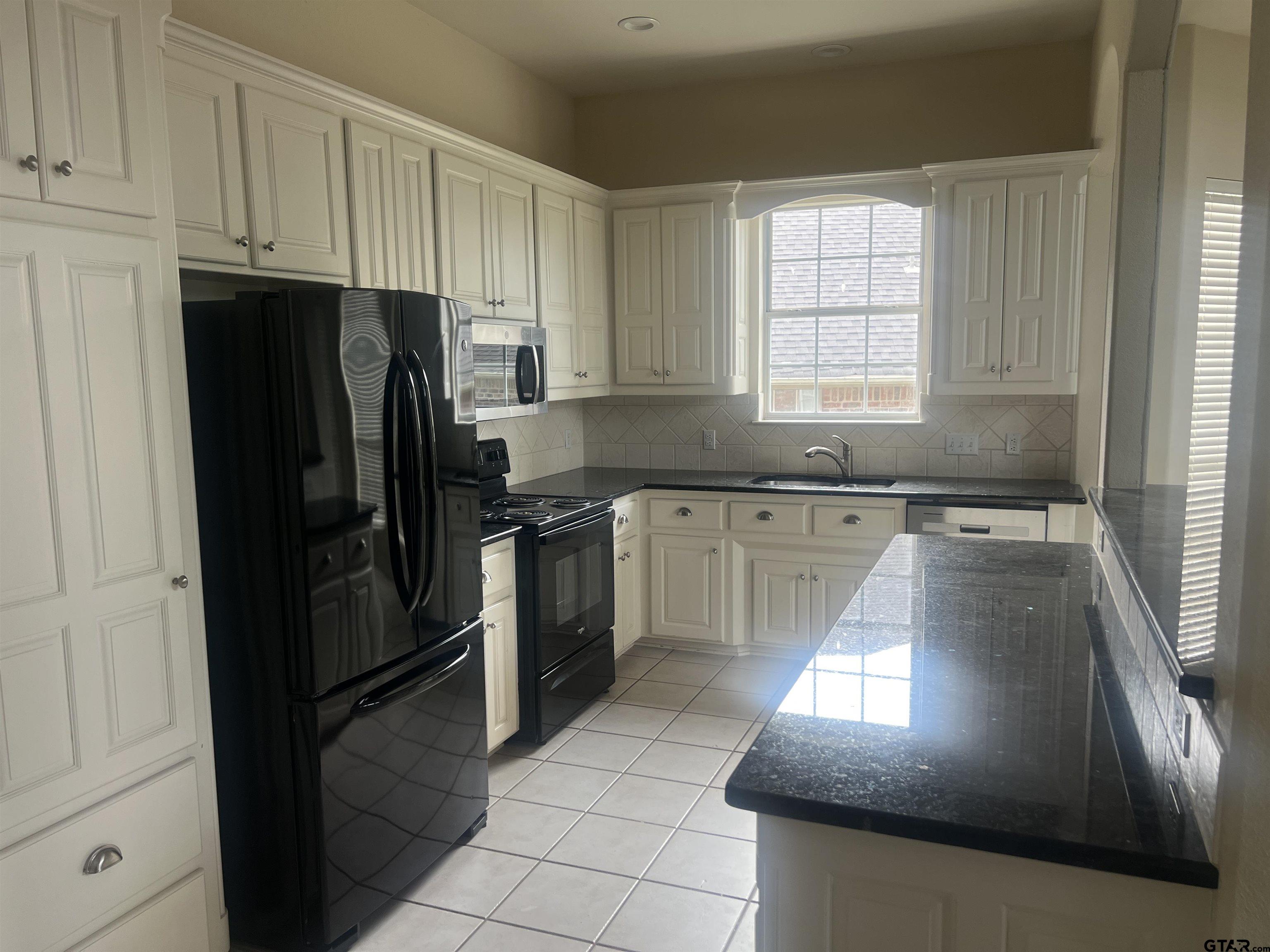1805 Oak Ridge Street Hideaway, TX 75771 - Photo 3 of 15 a kitchen with granite countertop a refrigerator a sink a stove and cabinets