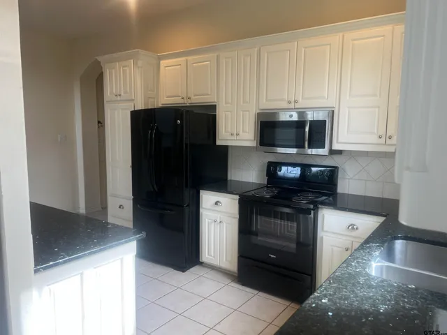 a kitchen with stainless steel appliances granite countertop a refrigerator and a stove