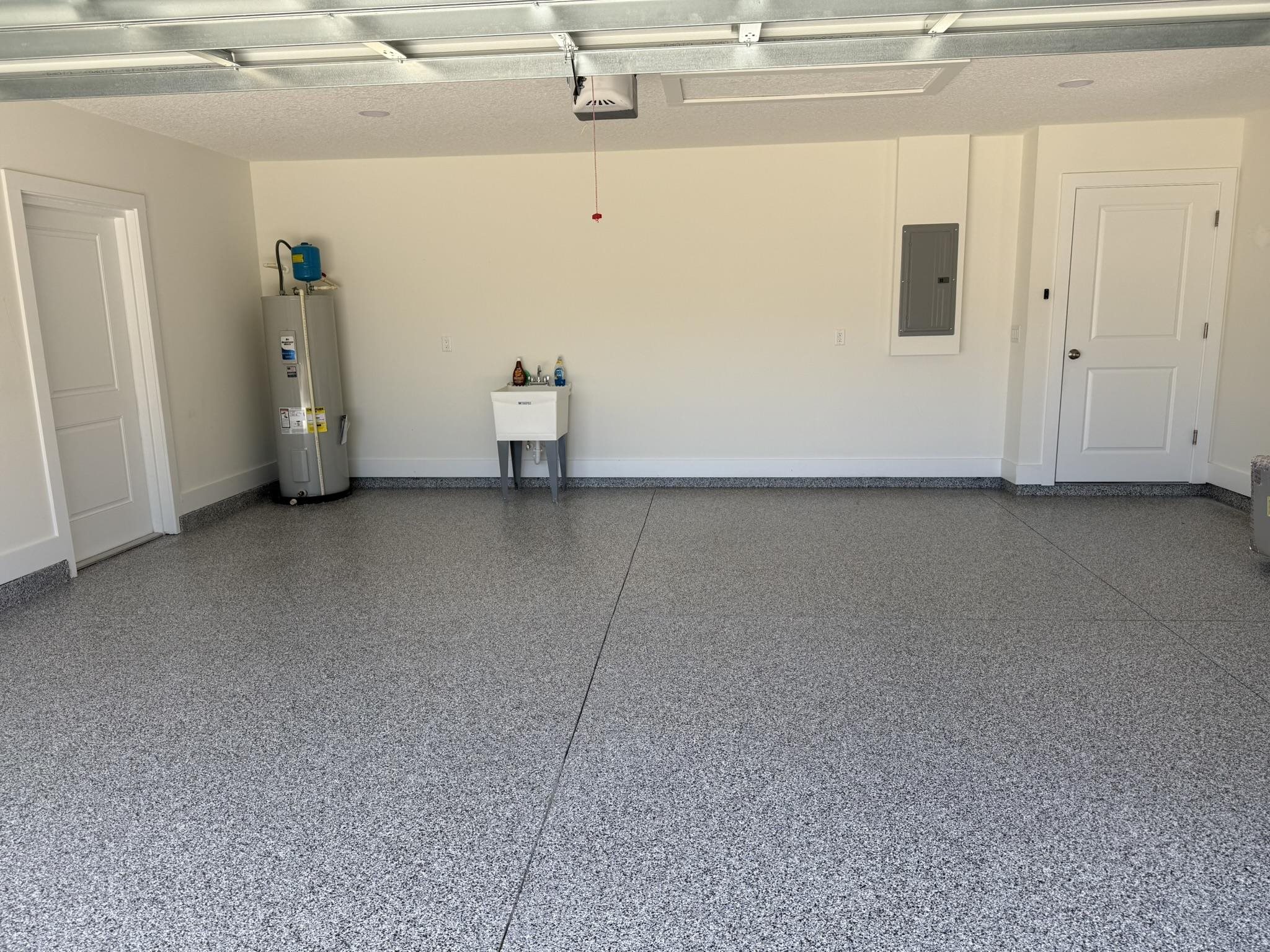 611 Queen Road St. Augustine, FL 32086 - Photo 14 of 17 Garage with electric water heater, electric panel, garage sink, custom epoxy floor, and a garage door opener