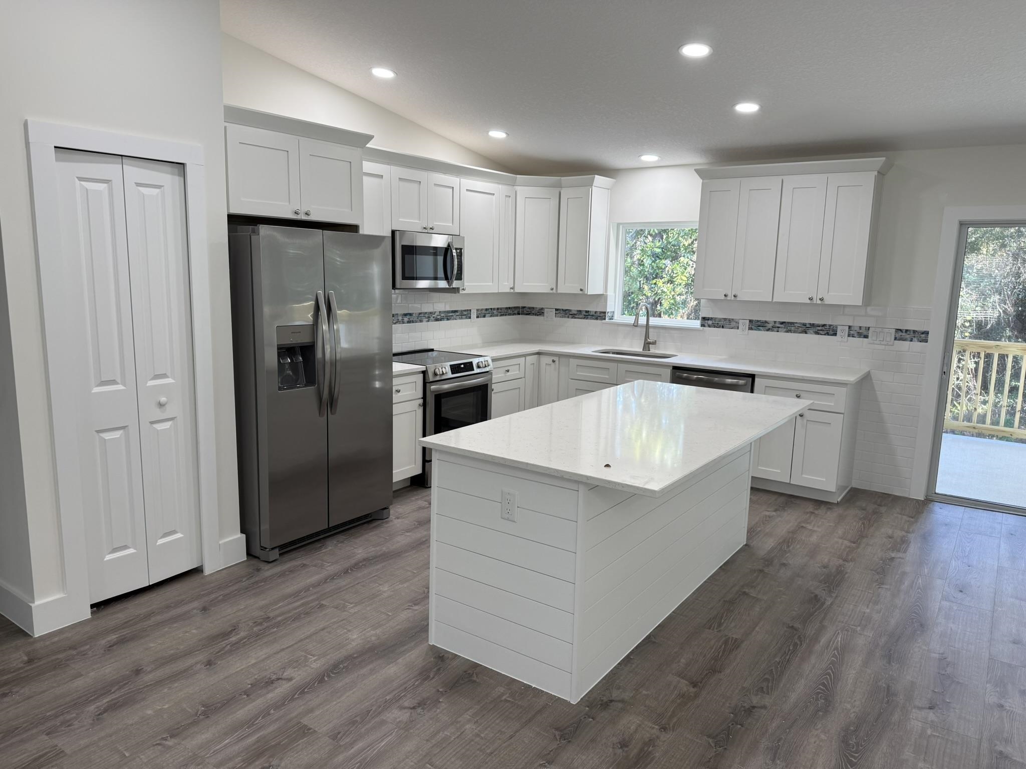 611 Queen Road St. Augustine, FL 32086 - Photo 3 of 17 Kitchen featuring appliances with stainless steel finishes, white cabinets, lofted ceiling, a kitchen island, and tasteful backsplash