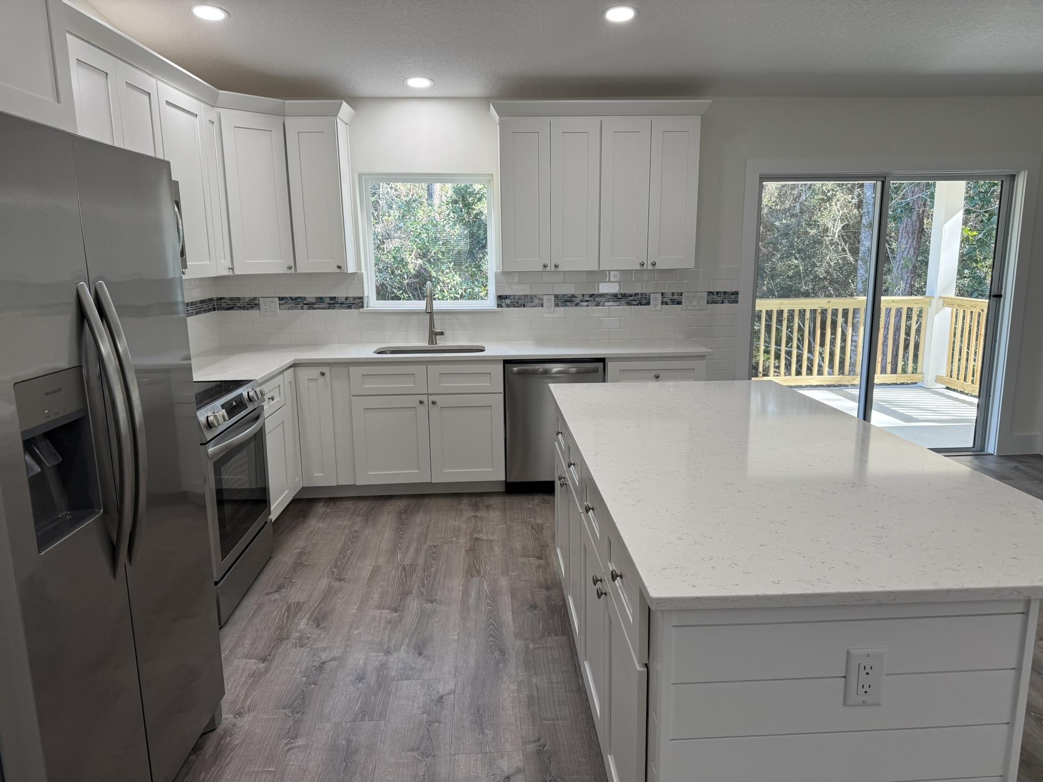 611 Queen Road St. Augustine, FL 32086 - Photo 4 of 17 Kitchen featuring appliances with stainless steel finishes, white cabinets, quartz counters, and backsplash