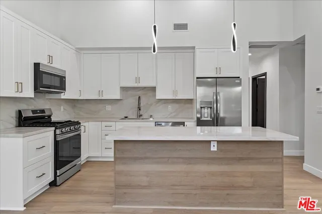 a large kitchen with stainless steel appliances granite countertop a stove a sink and a refrigerator