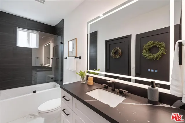 a bathroom with a granite countertop sink toilet a mirror a bathtub and shower