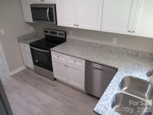 a kitchen with granite countertop stainless steel appliances sink and cabinets