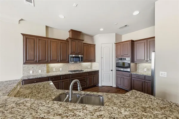 a kitchen with stainless steel appliances granite countertop a sink stove and refrigerator