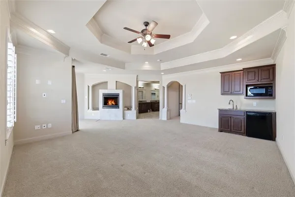 a view of an empty room with a fireplace and a ceiling fan