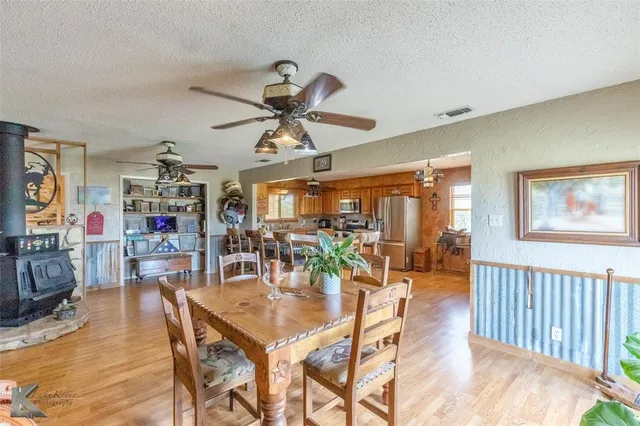 a dining room with wooden floor a chandelier a glass table and chairs