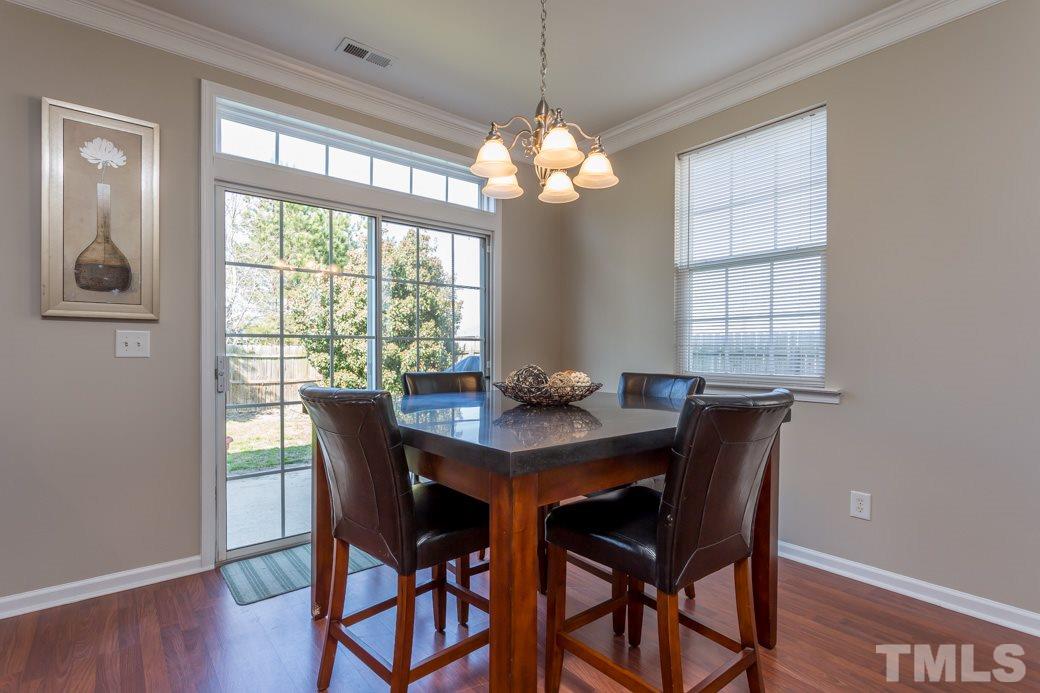 3709 Marshlane Way Raleigh, NC 27610 - Photo 4 of 9 a dining room with wooden floor a chandelier a wooden table and chairs