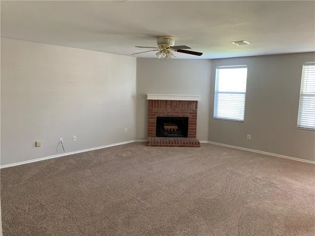 an empty room with windows and fireplace