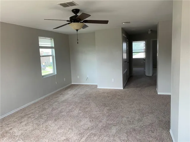 an empty room that has a window and a ceiling fan