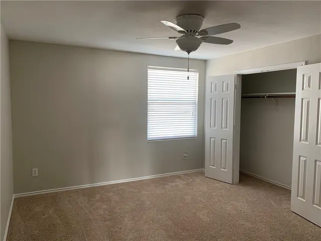 an empty room with a ceiling fan and a window