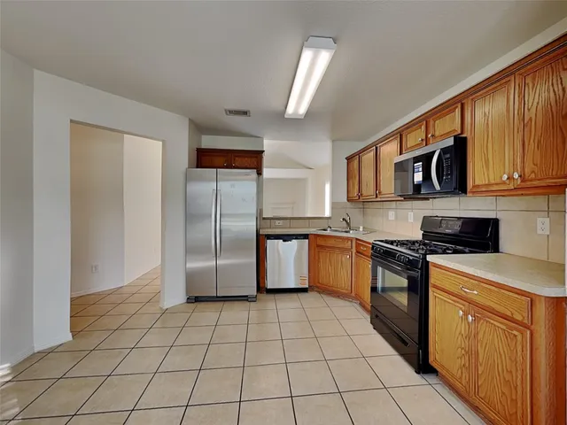 a kitchen with stainless steel appliances granite countertop a stove a sink and a refrigerator