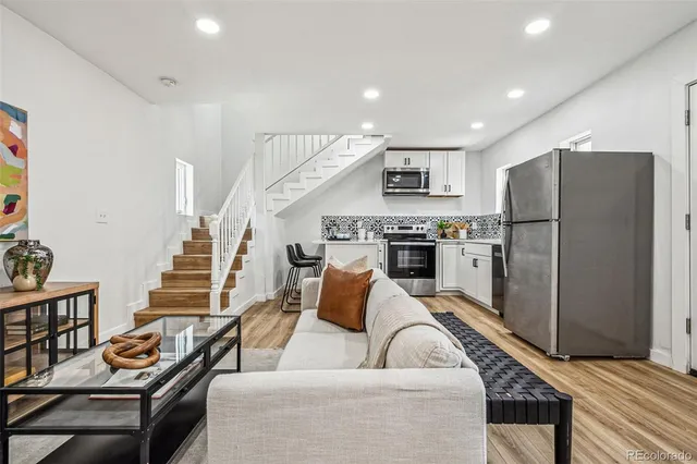 a living room with furniture kitchen and a refrigerator