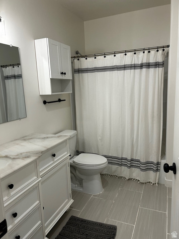 315 South Sherman Street Mapleton, UT 84664 - Photo 14 of 30 Bathroom featuring a white vanity with a stone-finish countertop, coordinating overhead cabinetry, a white toilet, and large format floor tiling