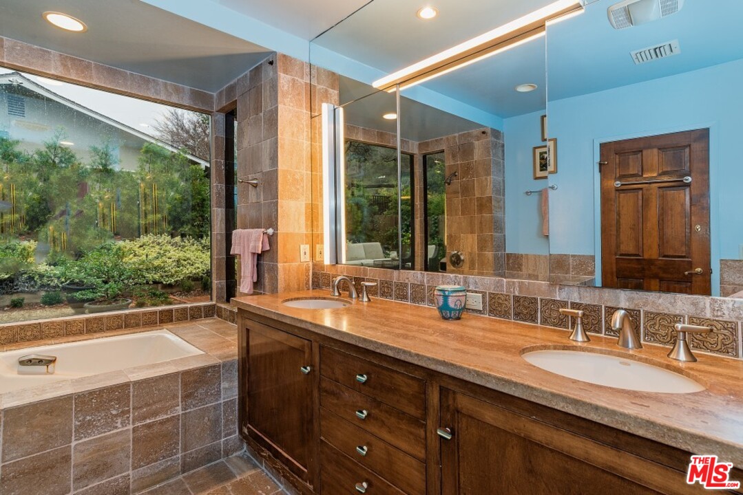 3266 Mandeville Canyon Road Los Angeles, CA 90049 - Photo 17 of 37 a bathroom with a granite countertop sink mirror bathtub and double